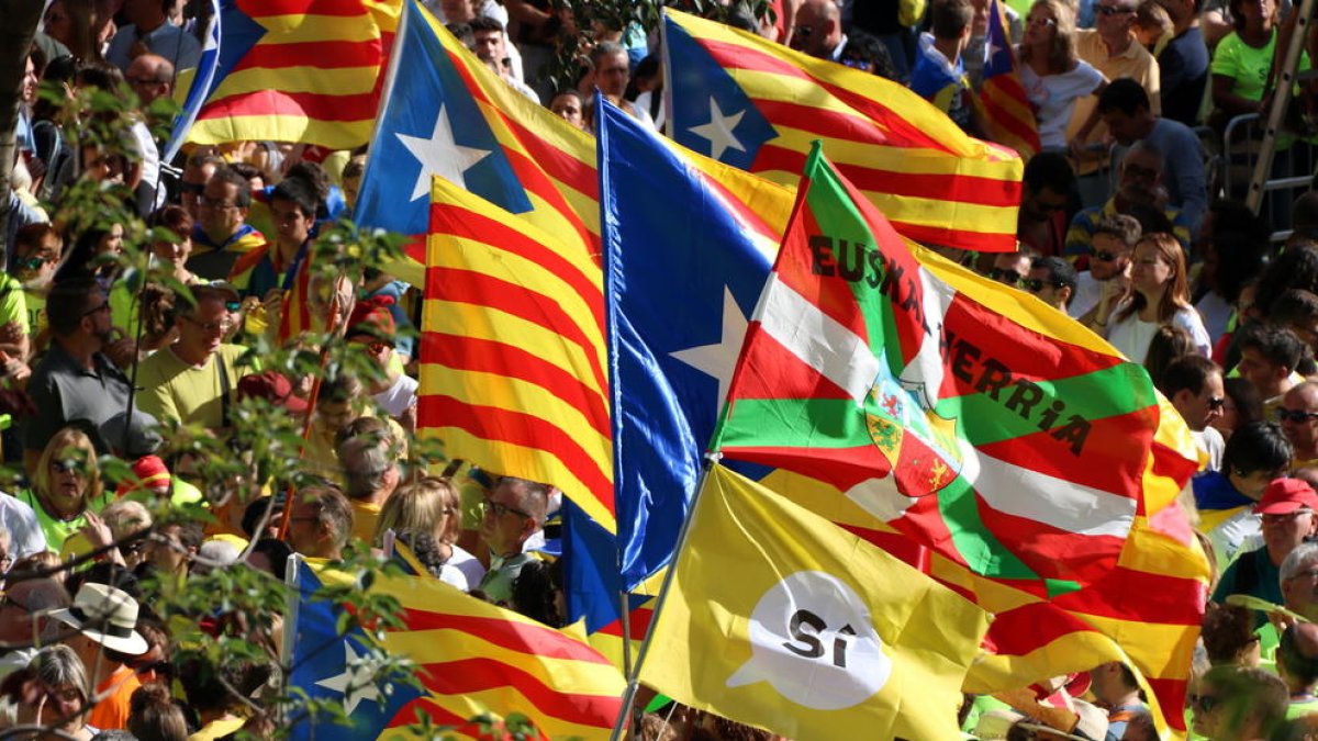 Diverses banderes estelades i senyeres, amb una bandera basca i una altra a favor del 'sí' a la independència, durant la manifestació de la Diada de l'11 de setembre de 2017.