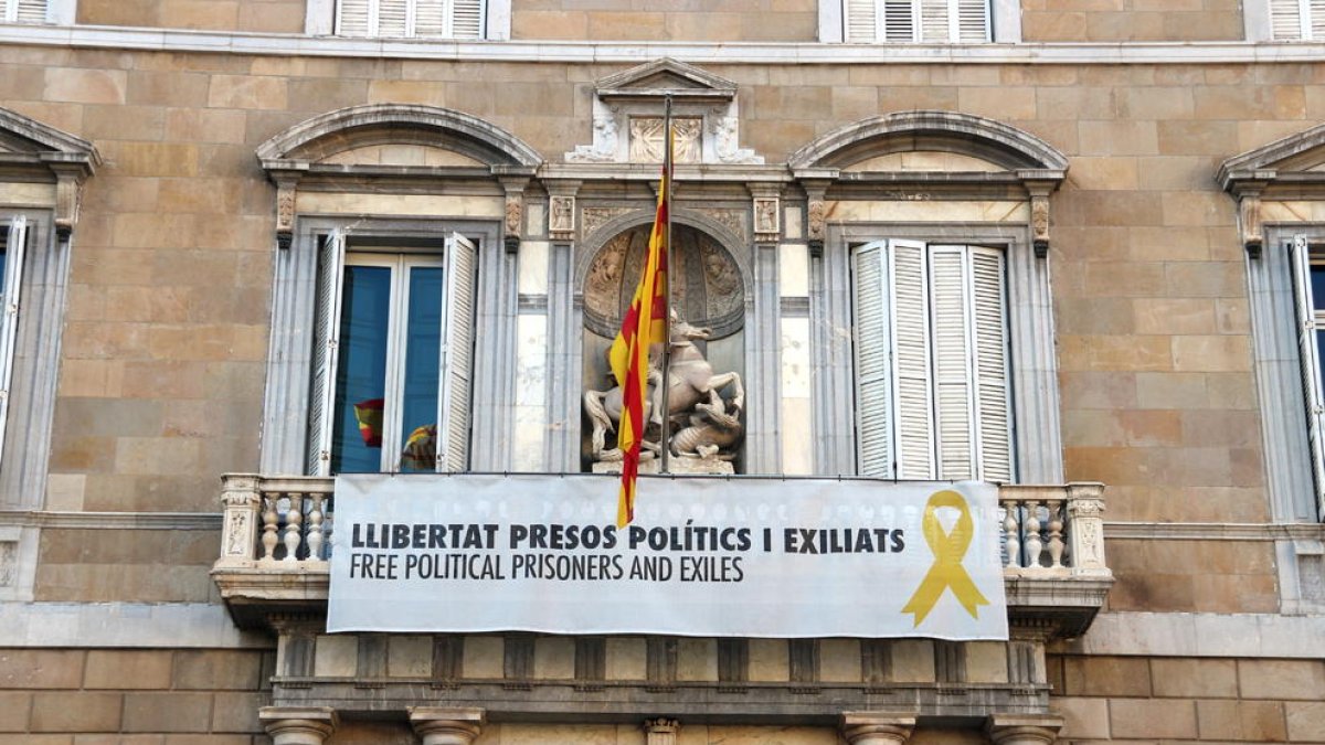 Part central de la façana del Palau de la Generalitat amb la pancarta amb el llaç groc penjats.