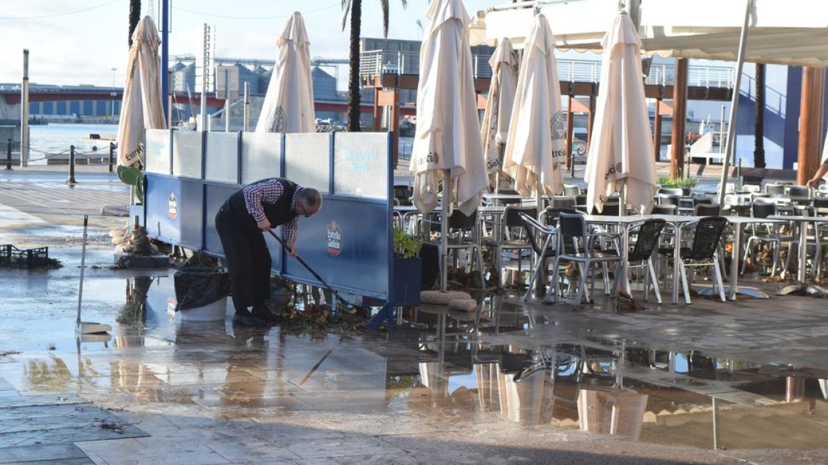 Un treballador d'un restaurant del Carrer Trafalgar netejant la terrassa.