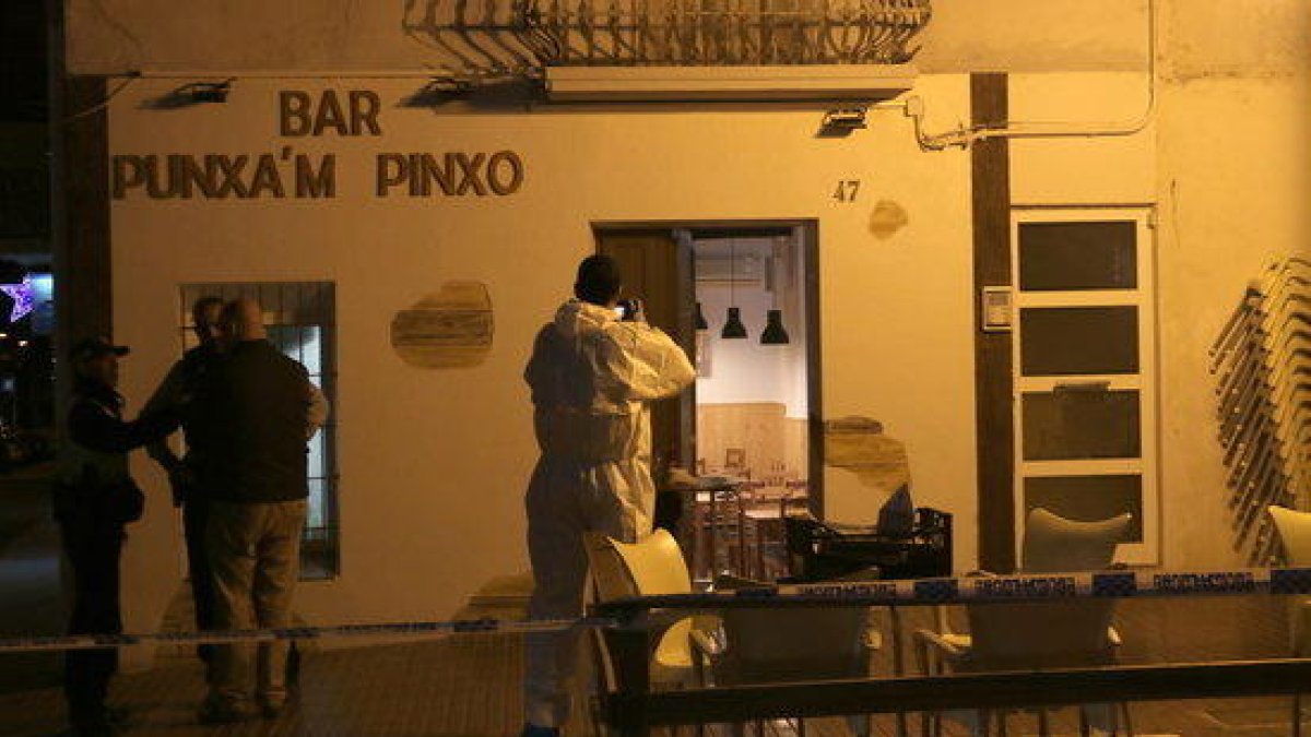 Un agent de la policia científica dels Mossos fent fotos de la façana del bar Punxa'm Pinxo de Sant Carles de la Ràpita el 13 de desembre de 2017.