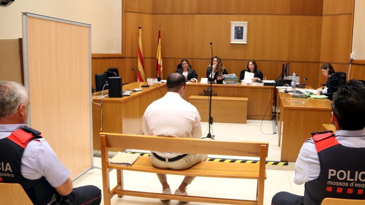 Imagen del policía acusado, sentado de espaldas, en la sala de vistas de la Audiencia de Barcelona.