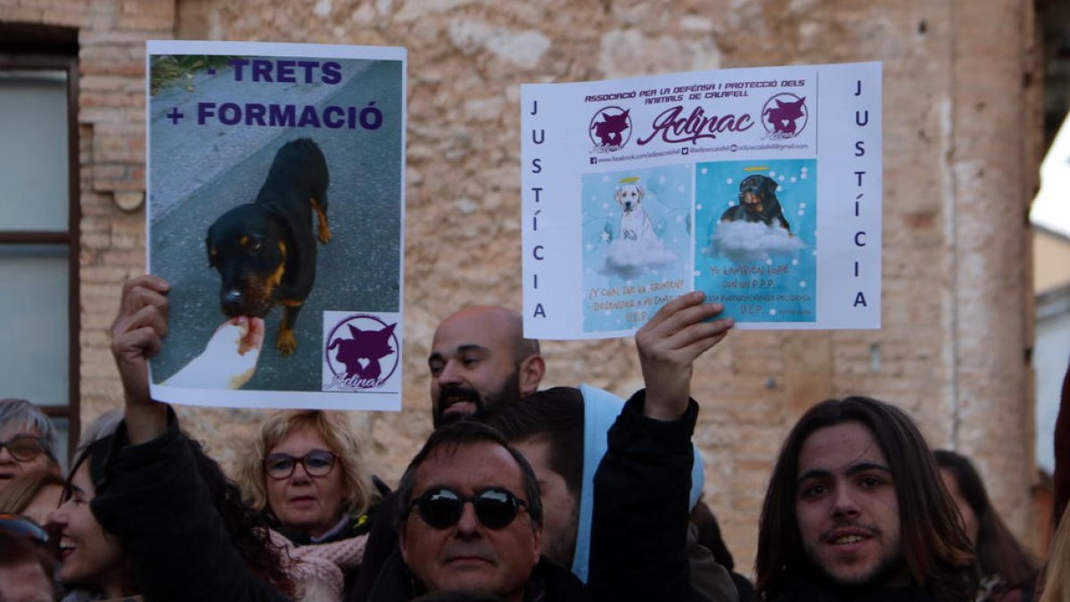 Dos manifestants alçant cartells reivindicatius en la protesta per la mort d'un rottweiler abatut per la Policia Local de Calafell.