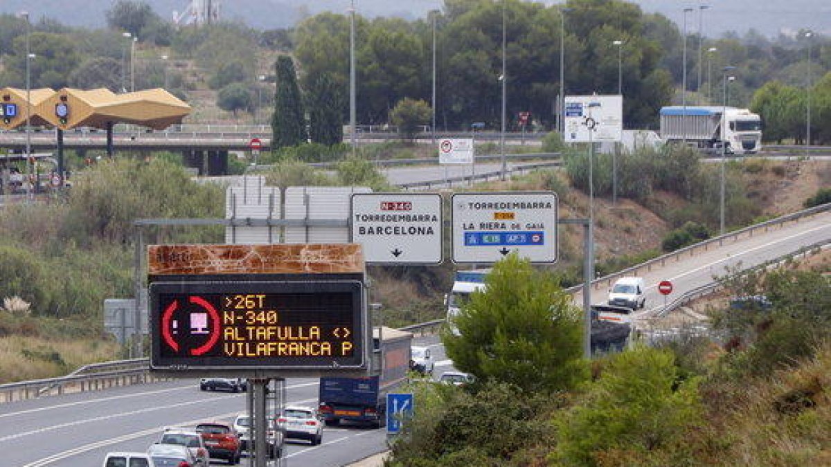 Plano abierto de un letrero luminoso que informa de la restricción de paso de camiones por la N-340, hasta Vilafranca Sud, a la altura del acceso del peaje de Altafulla-Torredembarra.