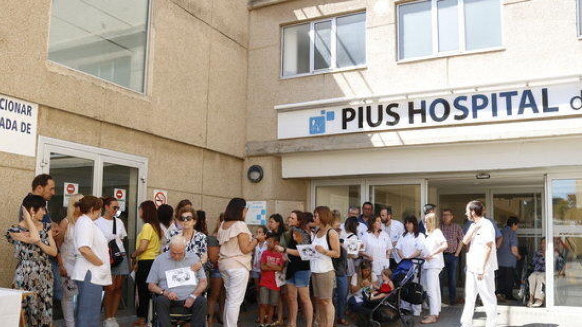 Plano general de una cincuentena de trabajadores de Pius Hospital de Valls concentrados delante de las puertas del centro hospitalario.