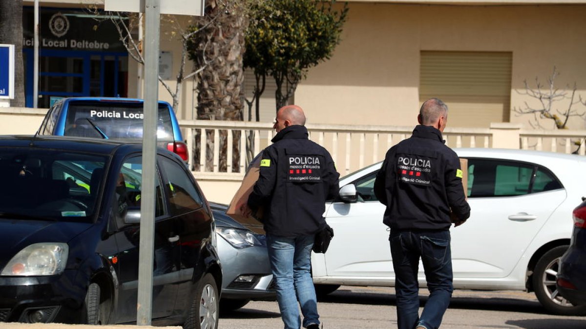 Dos agents dels Mossos d'Esquadra portant caixes de documentació que han requisat a l'Ajuntament de Deltebre a un vehicle policial.