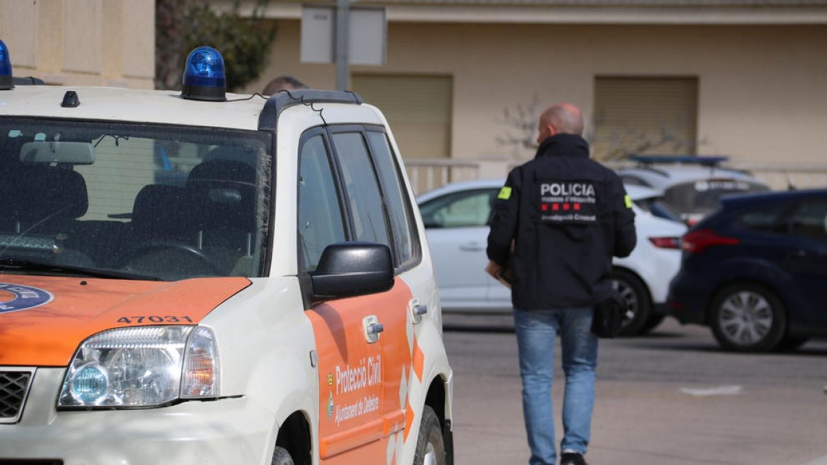 Un vehículo de protección civil en Deltebre con uno agentes de los Mossos saliendo del Ayuntamiento con cajas de documentación.