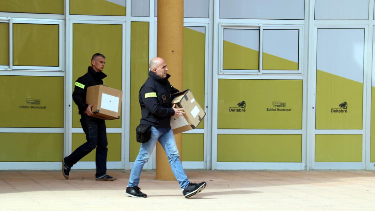 Pla general de dos agents dels Mossos d'Esquadra amb caixes sortint de l'Ajuntament de Deltebre.