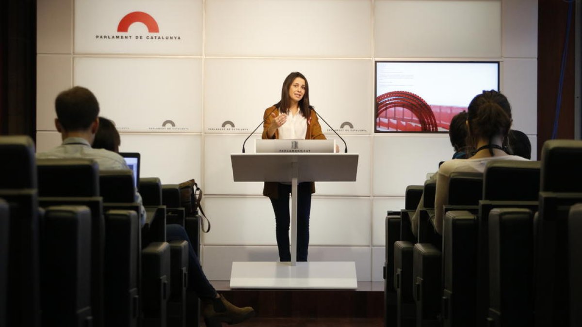 Las butacas de la sala de prensa del Parlamento en primer término y la líder de Cs, Inés Arrimadas.