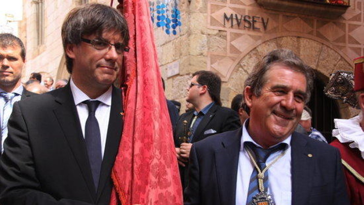 El presidente de la Generalitat, Carles Puigdemont, lleva la bandera de la Villa Ducal al lado del alcalde de Montblanc, Josep Andreu, en una imagen de archivo.