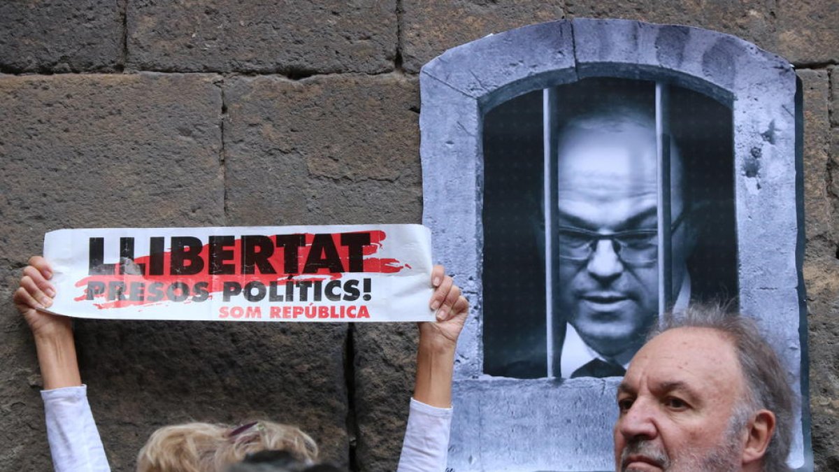 Un cartell demana la llibertat dels «presos polítics» amb una imatge del conseller destituït Jordi Turull al costat, a la plaça del Rei de Barcelona.
