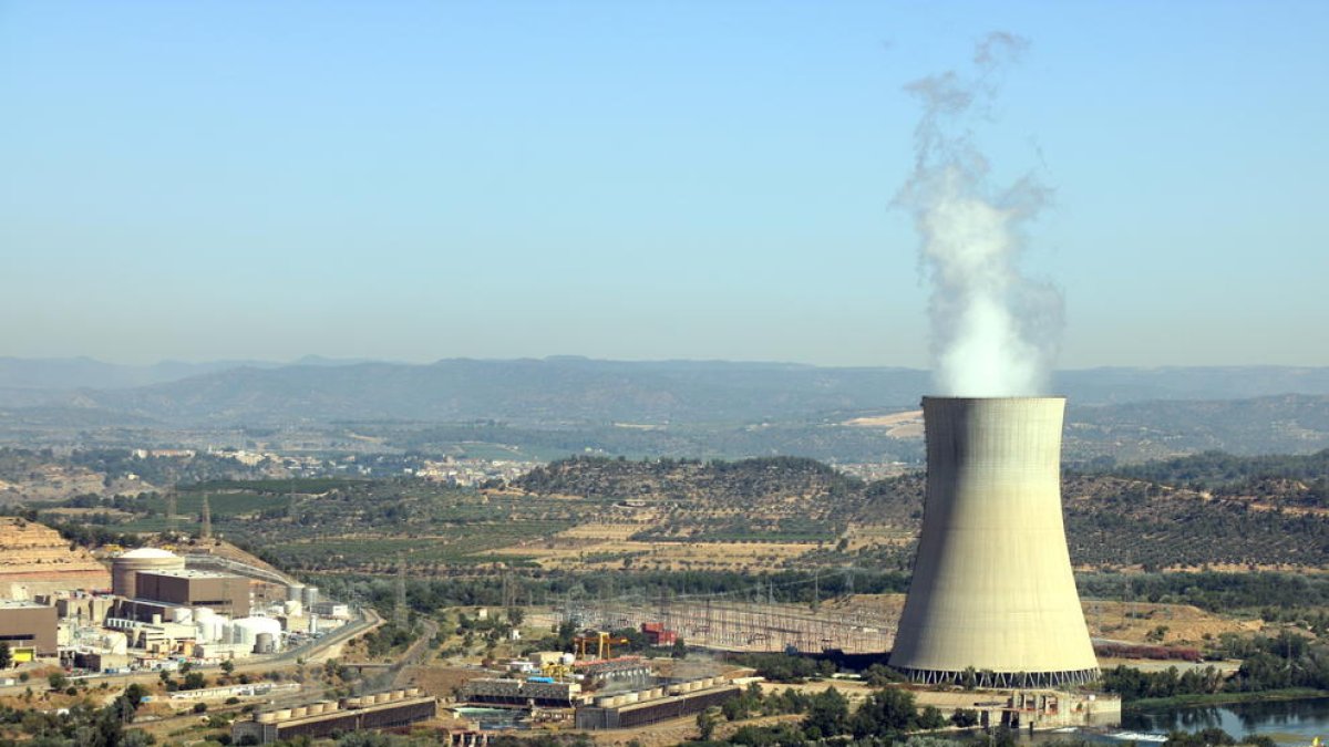 Imatge de la central nuclear d'Ascó, a la Ribera d'Ebre, amb la xemeneia fumejant a la dreta i els dos reactors a l'esquerra.