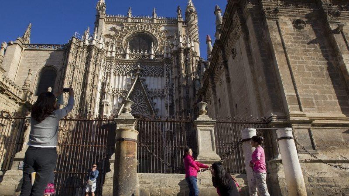 Imagen de archivo de unas turistas haciendo fotografías a lacatedral de Sevilla.