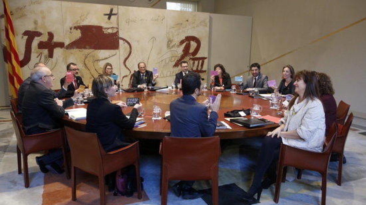 Imagen de la reunión del consejo ejecutivo. El presidente y los consellers muestran unas cartulinas con fragmentos de poemas que la consellera Borràs les ha repartido.