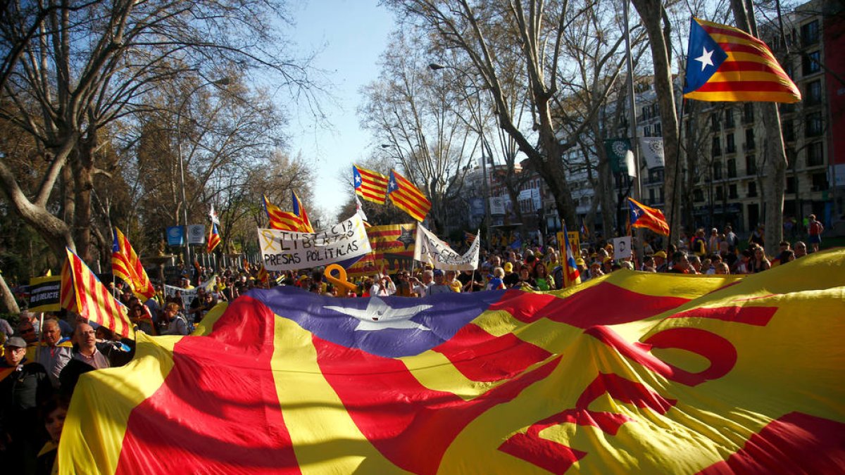 Imagen de la estelada, en primer término, y los manifestantes en Madrid con carteles y banderas.