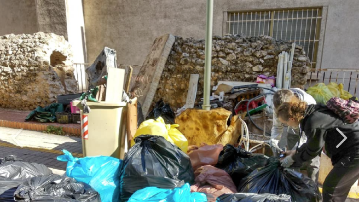 Imagen de una voluntaria acumulando la basura recogida.