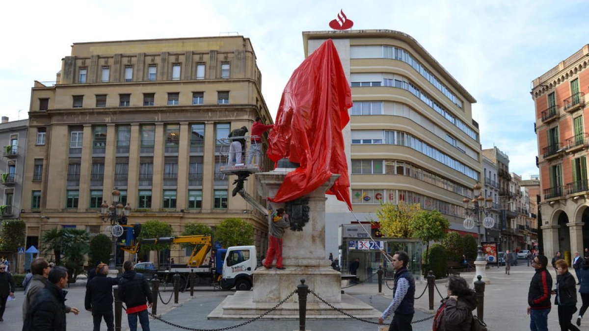 Imatge de l'estatua de la Plaça Prim coberta amb una tela vermella