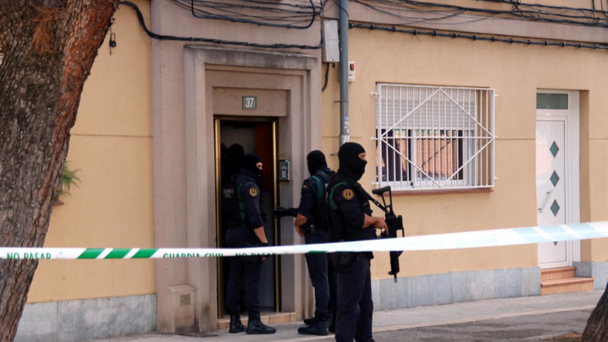Diversos agents de la Guàrdia Civil a la porta d'un habitatge del carrer Goya de Sabadell on estan duent a terme un escorcoll.