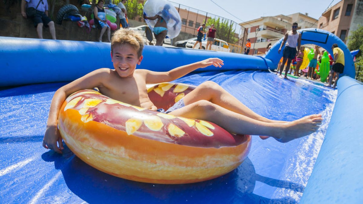 Un niño bajando por el tobogán acuático, ayer, en la calle Joan Maragall de Castellvell del Camp, durante las fiestas de Santa Anna.