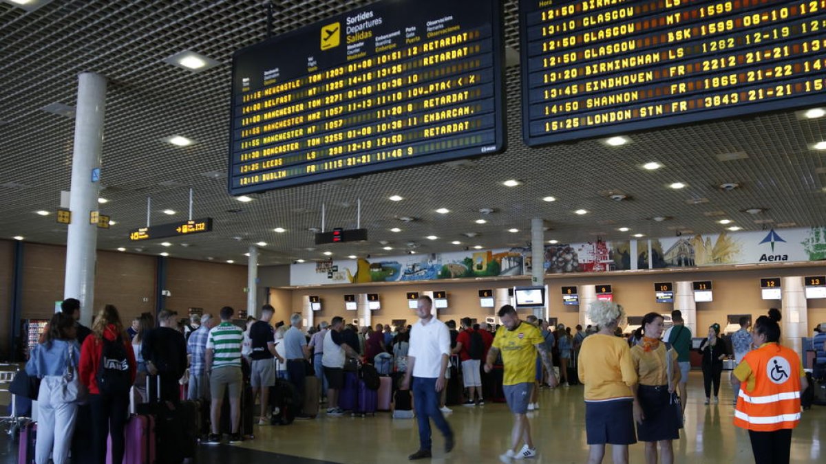 Pla general de cues per facturar a l'Aeroport de Reus i del panell informatiu que indica retards en els vols amb destinació al Regne Unit que operava la companyia Thomas Cook. Imatge del 24 de setembre del 2019. (Horitzontal) Vincular  Crear
