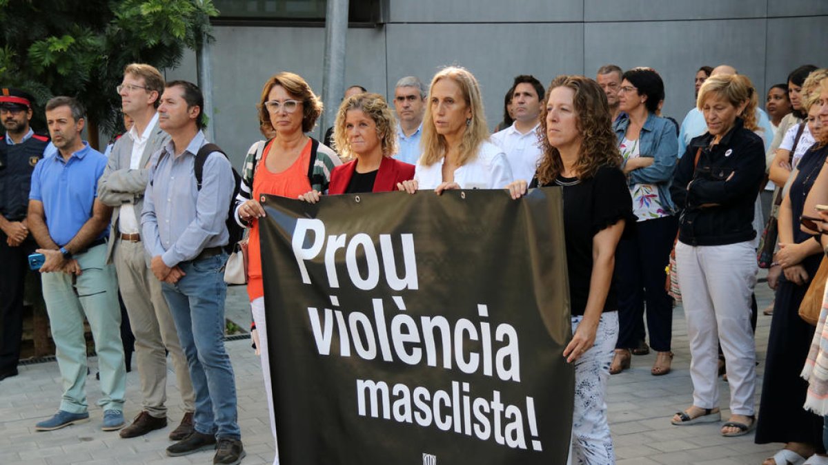 Plano general de las personas concentradas y la pancarta desplegada durante el minuto de silencio para recordar a la mujer muerta a manos de su hijo el pasado viernes en Tortosa.