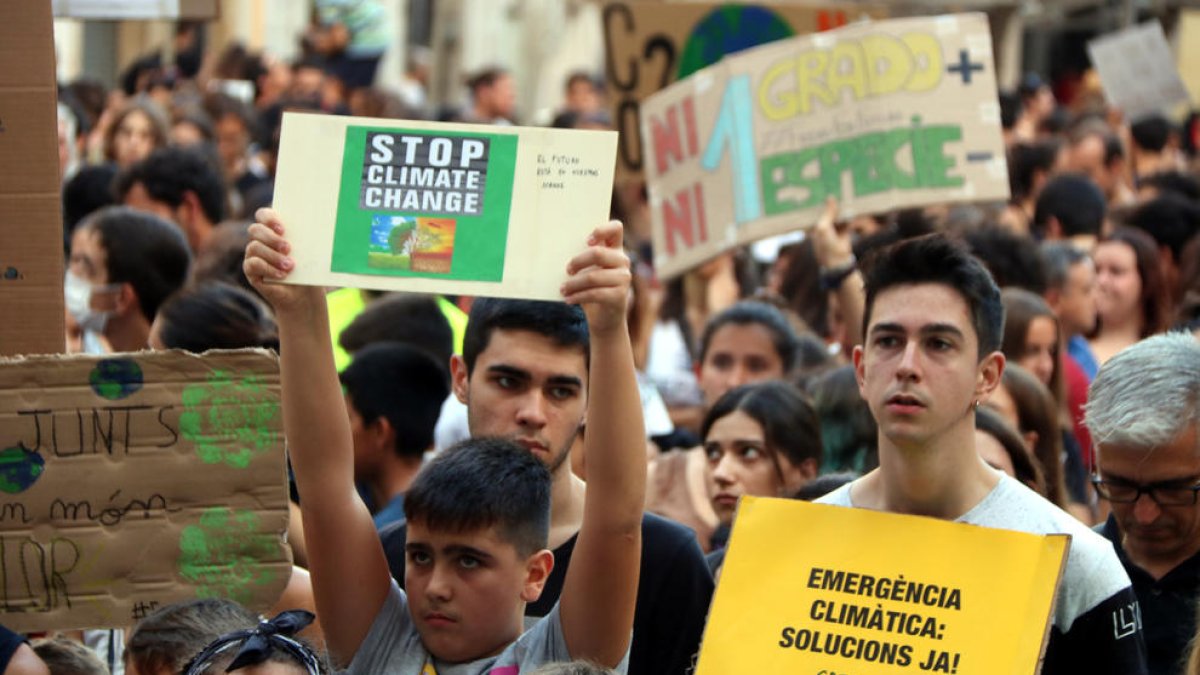 Pla mitjà d'un nen i un noi mostrant cartells contra el canvi climàtic a la plaça de la Font de Tarragona, el 27 de setembre del 2019