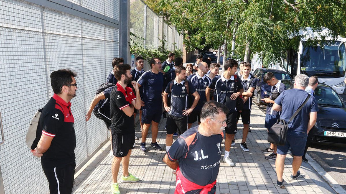 Los jugadores y cuerpo técnico del Rubí y los árbitros esperando fuera del campo.