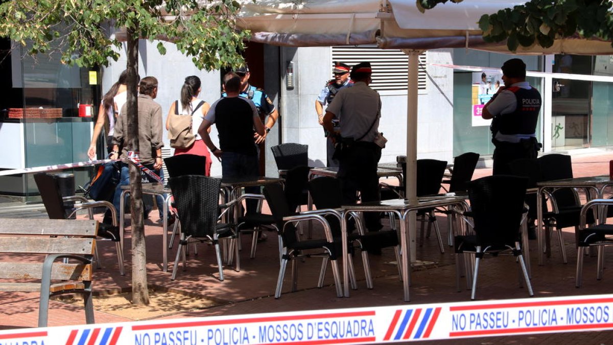 Imagen del precinto y agentes de las fuerzas policiales en la puerta del edificio de Terrassa donde se produjeron los hechos.