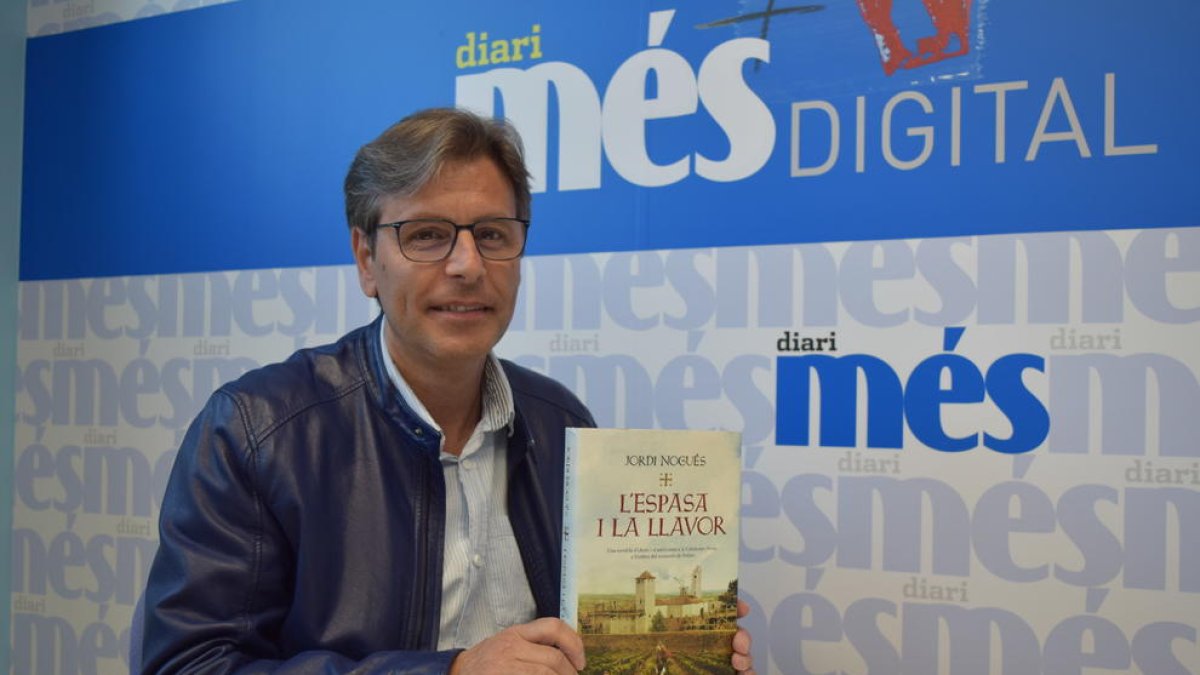 Jordi Nogués sostiene en sus manos un ejemplar de la novela 'L'espasa i la llavor'.