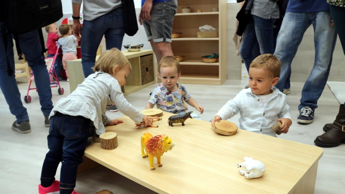 Tres niños que juegan en una mesa de un jardín de infancia.