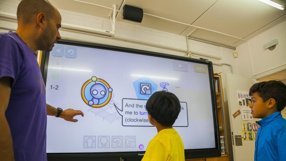 Moncusí explica a dos alumnos el funcionamiento de un panel interactivo que ha incorporado la escuela.