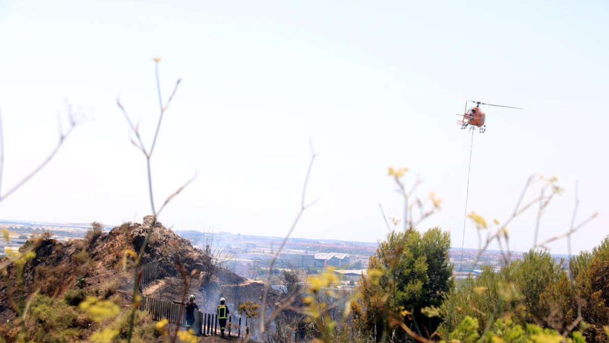 Bombers treballen en l'extinció de l'incendi al turó de Montjuïc de Barcelona on hi ha les ruïnes del Castell de Port.