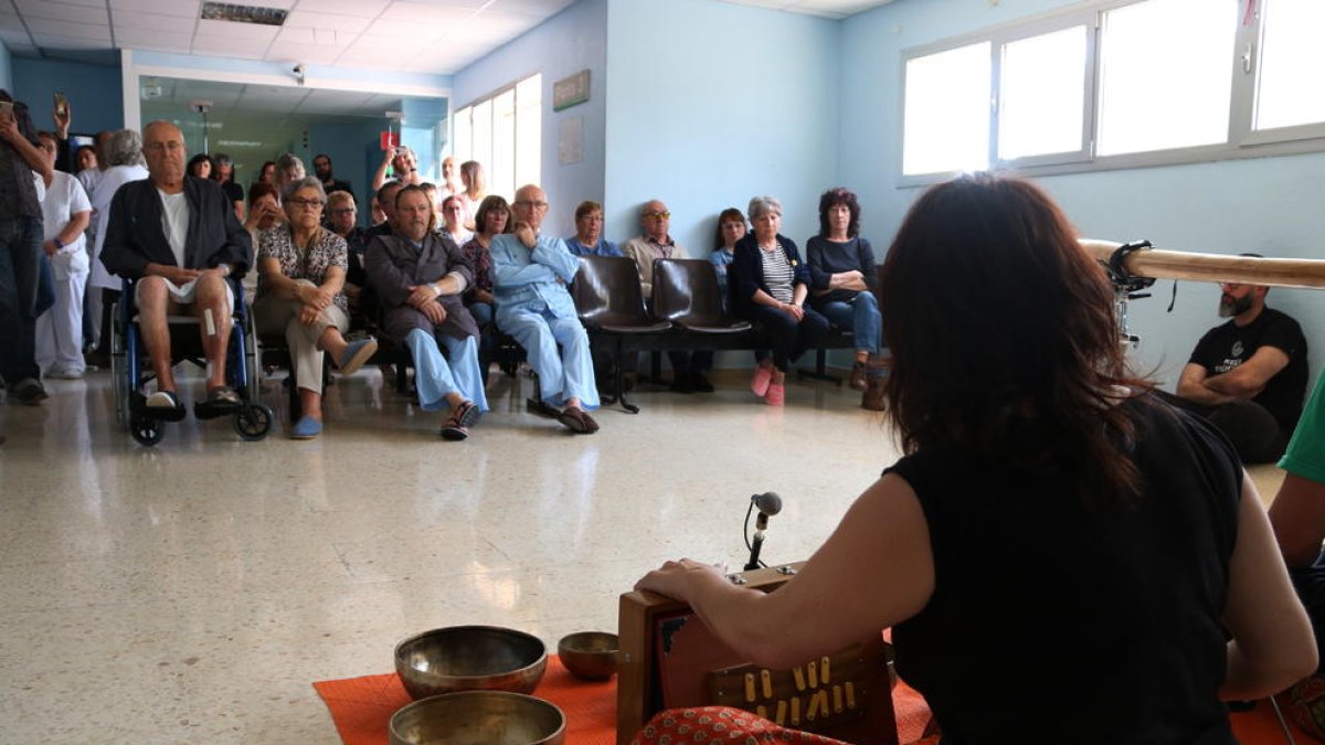 Uno de los miembros del dúo IOMA de espaldas y los usuarios en el fondo durante la acción sonora hecha al hospital Verge de la Cinta de Tortosa.