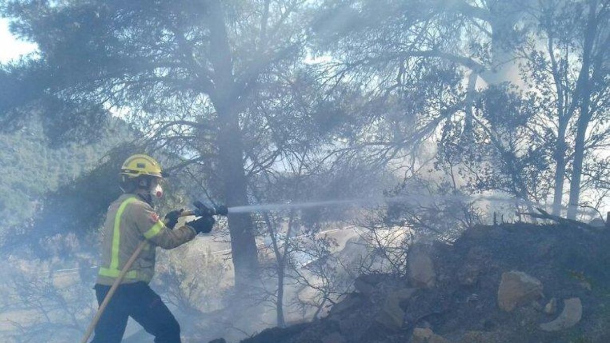 Un bomber amb la mànega treballant a l'incendi.