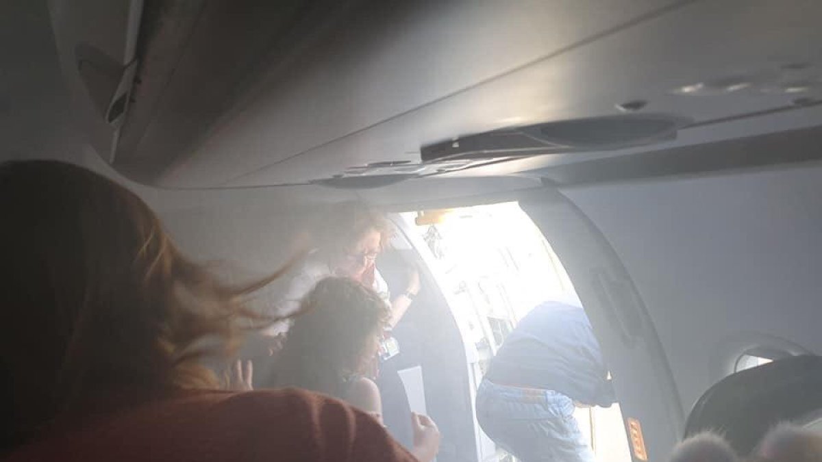 Diversos passatgers sortint de l'avió, plena de fum.