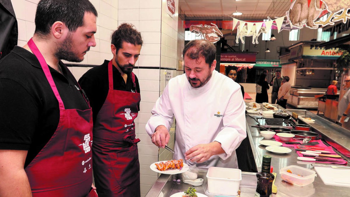 Un dels xefs convidats donant consells a dos cuiners d'un dels establiments participants.
