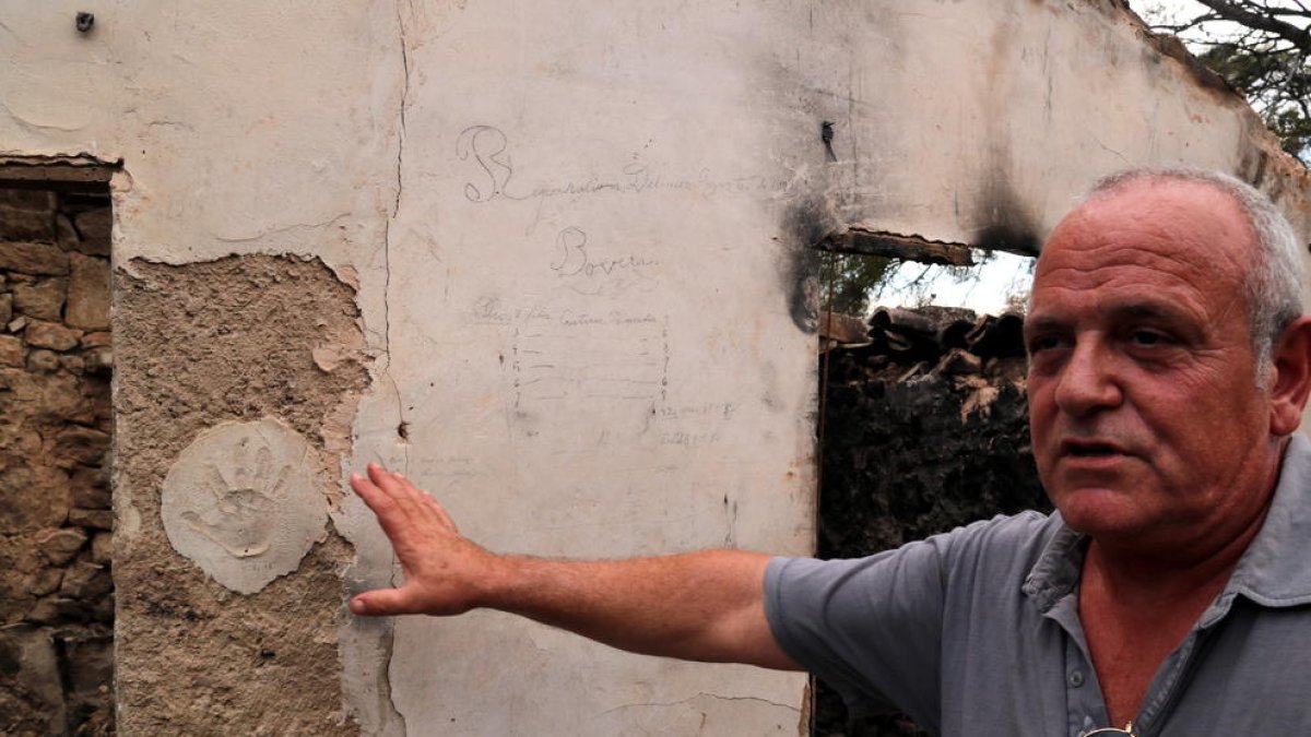 El campesino Enric Prunera señalando una de las paredes de su masía que se salvó de las llamas.