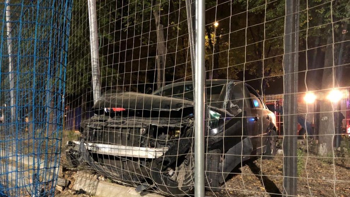 Imatge del cotxe encastat contra un petit mur i la xarxa del camp.