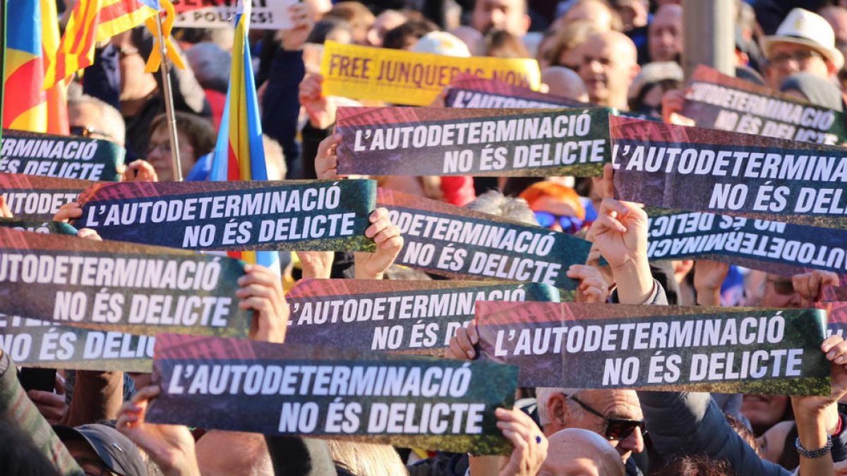 Un grupo de manifestantes sostienen carteles que dicen 'La autodeterminación no es delito' a la manifestación contra el juicio del 1-O en Barcelona.