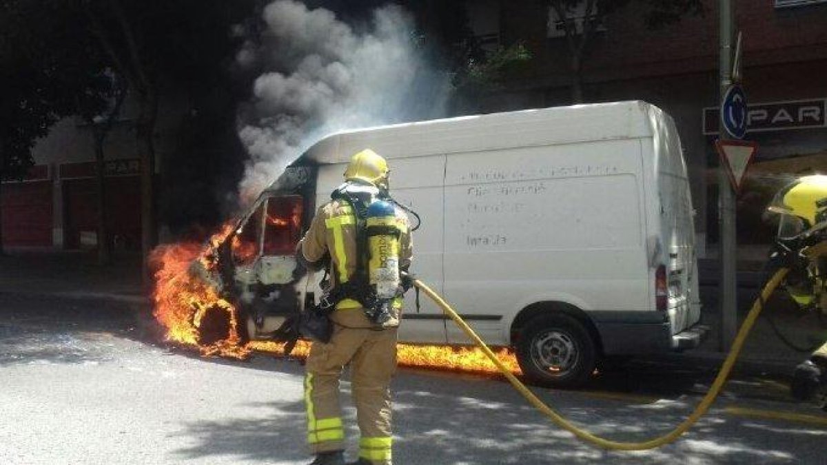 Imatge d'un Bomber treballant per apagar la furgoneta incendiada.