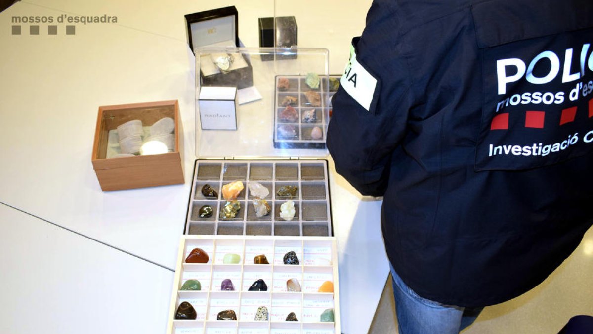 Un agente de los Mossos revisando parte de las colecciones de valor que el agresor robó a la víctima de la Sénia.