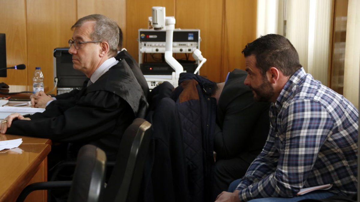 Plano cerrado de los dos acusados, en la derecha y uno de ellos tapándose con una chaqueta, en la Audiencia de Tarragona.
