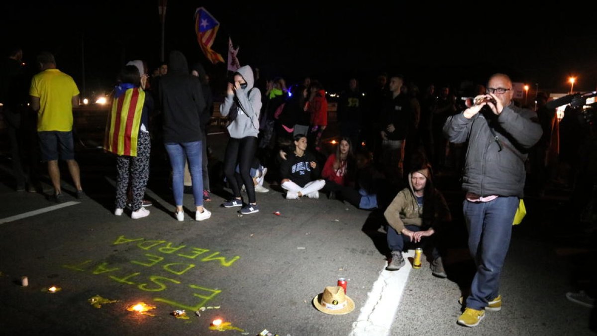 Alguns manifestants cantant al so de la gralla davant els escrits i les espelmes que han deixat a l'N-340 a Amposta.