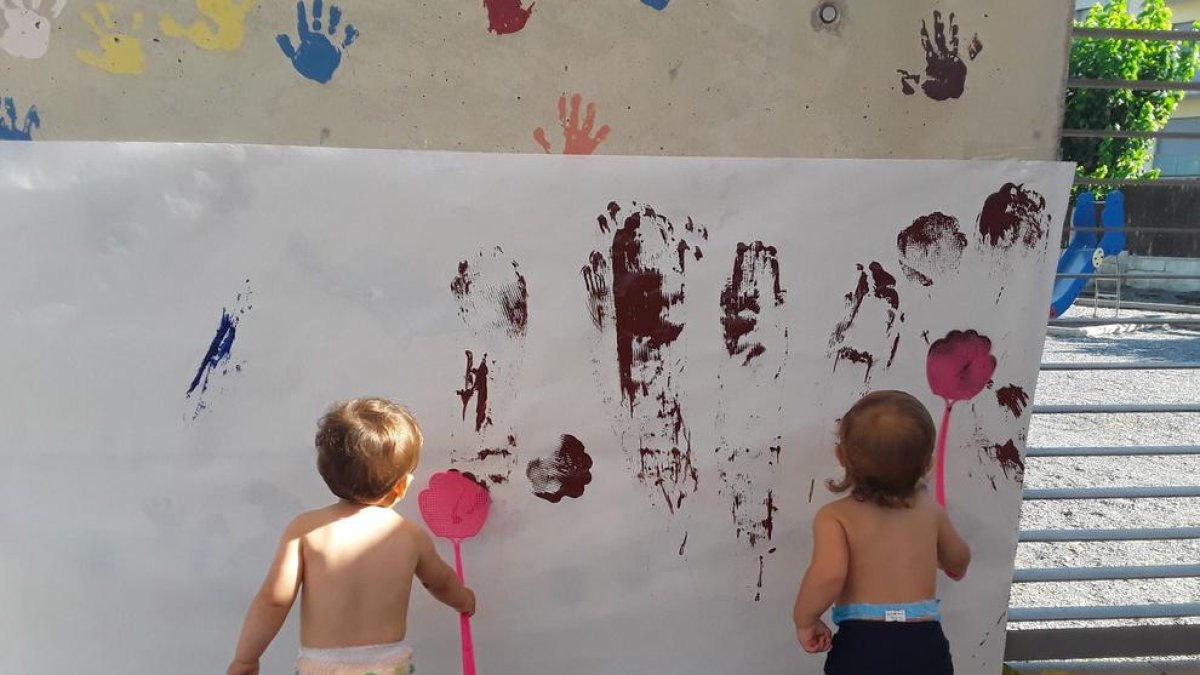 Dos niños pintando en una pared al jardín de infancia del Morell.