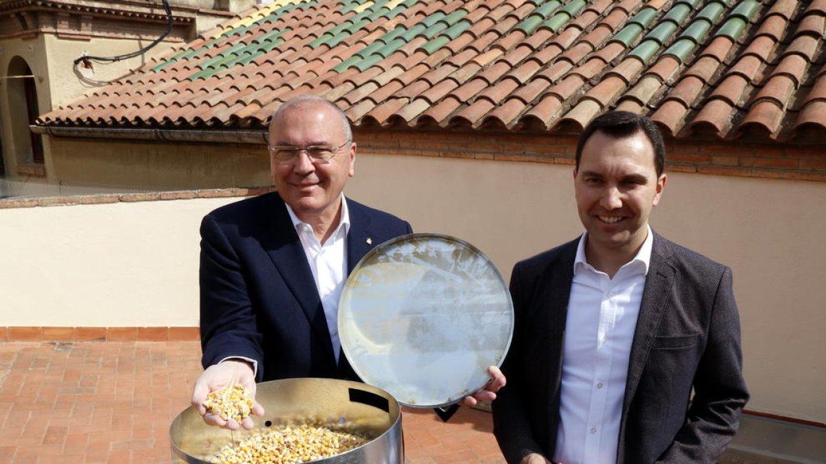 L'alcalde de Reus, Carles Pellicer, i el regidor de Medi Ambient, Daniel Rubio, al costat d'un dispensador de pinso anticonceptiu per a coloms que, durant uns dies, llençarà blat de moro.