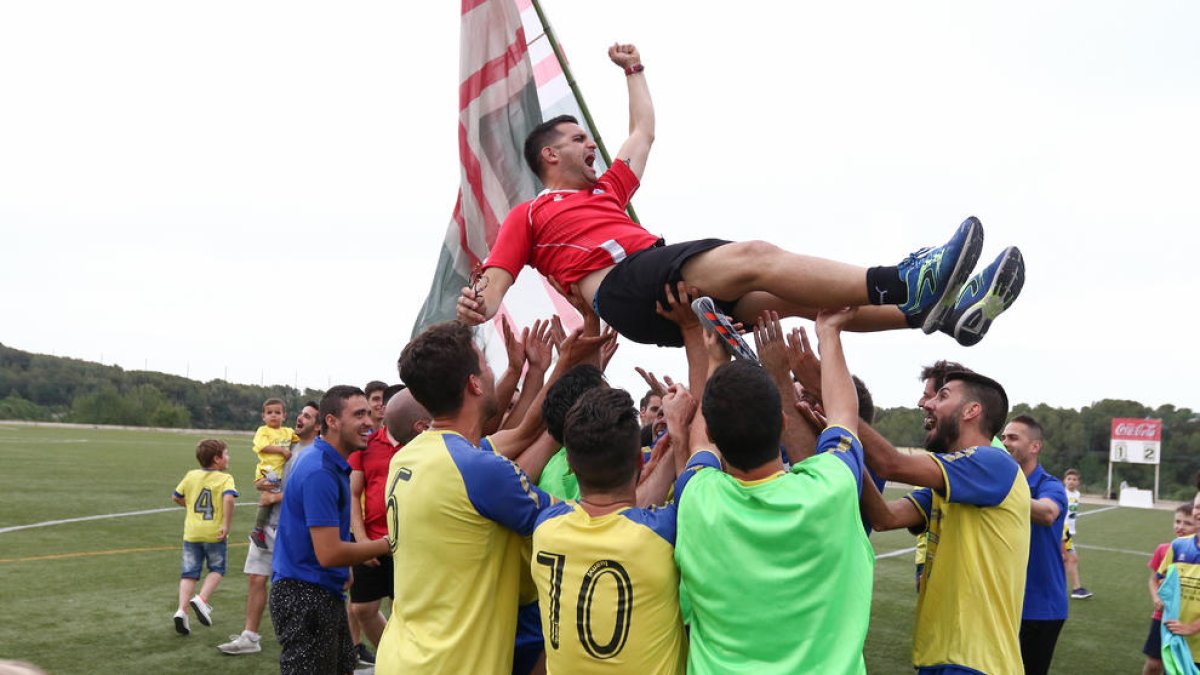 Els jugadors del Catllar celebrant l'ascens i mantejant al tècnic de l'equip.