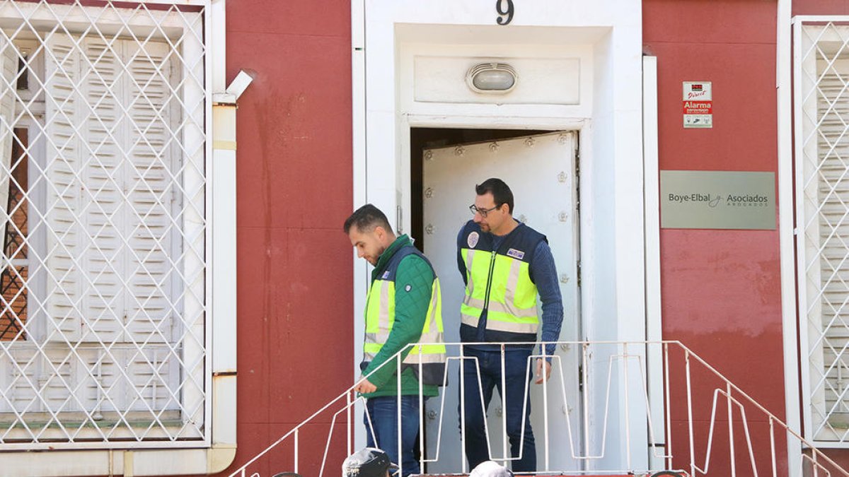 Dos agentes de paisano con chalecos amarillos de la Policía Nacional salen del despacho del abogado Gonzalo Boye.