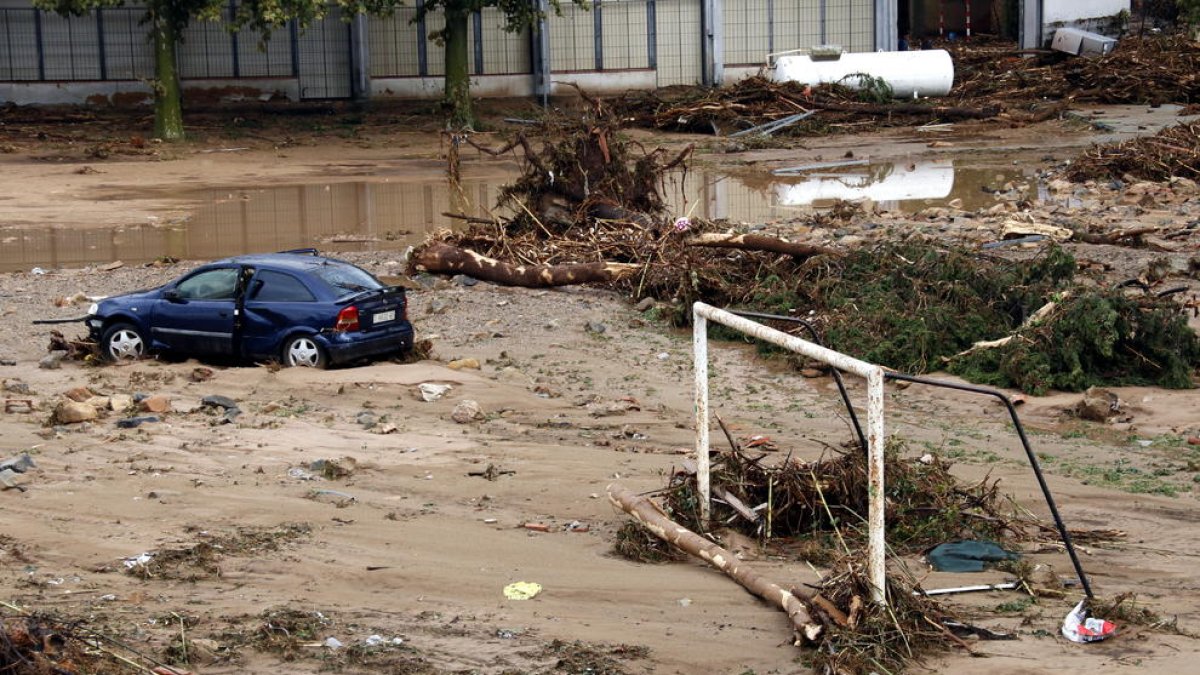 Pla picat d'una zona de Montblanc amb una porteria de futbol, un cotxe malmès i un dipòsit arrossegats entre el fang i els troncs que ha deixat la riuada. Imatge del 23 d'octubre del 2019 (horitzontal)