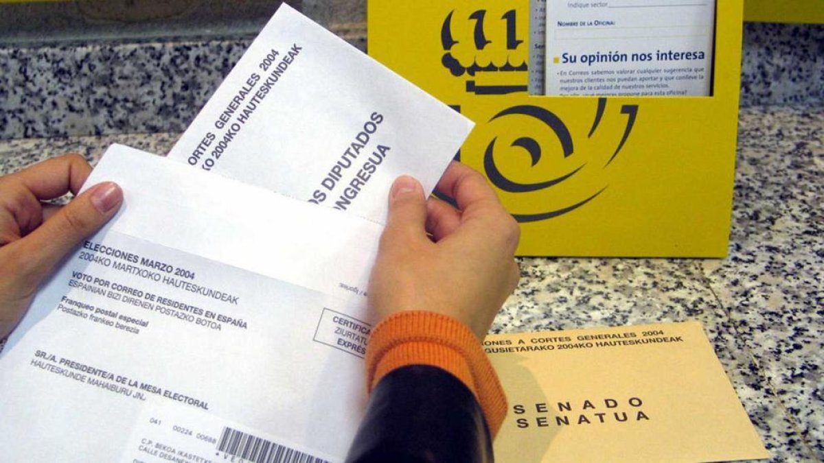 Imatge d'arxiu en la qual una ciutadana deposita el seu vot per correu en una oficina postal.