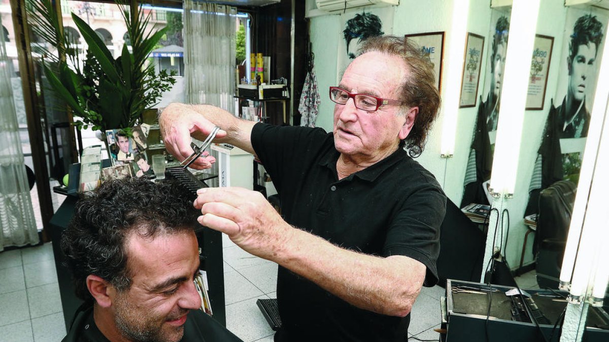 El perruquer Jordi Gimeno, que té el local a la plaça Prim, atenent un client, ahir.