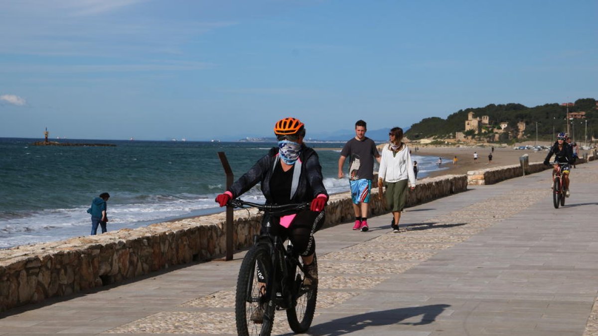 Cciclistes i persones caminant al passeig marítim d'Altafulla en el primer dia permès per sortir a passejar i practicar esport